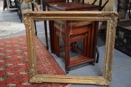 A giltwood picture frame and a picture of a young girl reading a book.