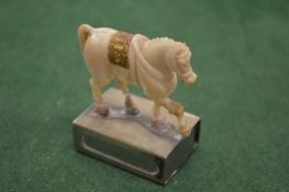A carved horse on a silver matchbox case.