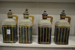 An unusual set of four Doulton Lambeth square shaped turquoise glazed stoneware liqueur bottles (one
