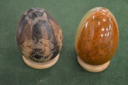 Two decorative hardstone eggs on stands.