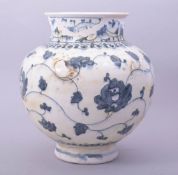 A PERSIAN SAFAVID BLUE AND WHITE GLAZED POTTERY VASE, decorated with flora and vine, 27cm high.