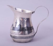 AN IRAQI SILVER AND NIELLO MILK JUG, decorated with river scene, 10cm high.