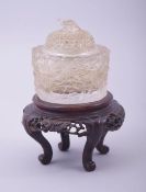 A SMALL CHINESE CUT GLASS LIDDED JAR with a hardwood stand, formed with multiple birds in flight,