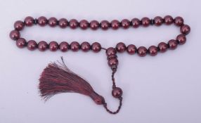 AN ISLAMIC CHERRY BAKELITE SET OF TASBIH PRAYER BEADS, comprising of 34 beads, two small dividing