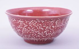 A CHINESE COPPER RED GLAZE BOWL, the exterior with raised decoration depicting dragon, phoenix and