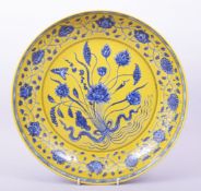 A LARGE CHINESE MING STYLE YELLOW GROUND BLUE AND WHITE DISH, the centre painted with a floral spray