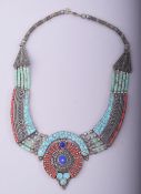 A TURQUOISE AND CORAL INSET WHITE METAL NECKLACE.