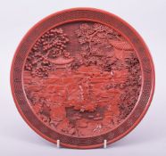 A CHINESE CINNABAR LACQUER CIRCULAR DISH, decorated with a landscape setting, the underside with