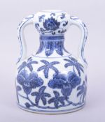 A CHINESE MING STYLE BLUE AND WHITE TWIN HANDLE VASE, decorated with banana leaf and flower, the