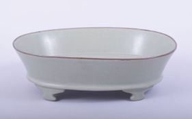 A LARGE CHINESE CELADON OVAL FORM WASHER, raised on four shaped feet, 23cm x 17cm.