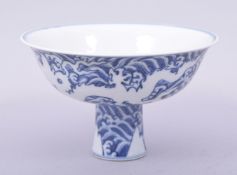 A CHINESE MING STYLE BLUE AND WHITE PORCELAIN STEM CUP, decorated with dragons amongst stylised