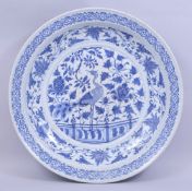 A LARGE CHINESE BLUE AND WHITE PORCELAIN CHARGER, central painted with a peacock amongst native