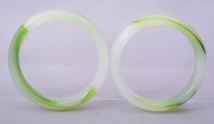 A PAIR OF CHINESE GREEN GLASS BANGLES, 8.5cm diameter.