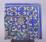 AN ISLAMIC BLUE AND WHITE GLAZED POTTERY TILE, with floral decoration, raised on a metal stand, tile