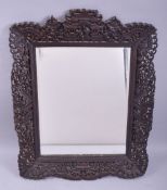 A CHINESE CARVED AND PIERCED WOODEN FRAMED MIRROR, the frame carved figures, temples and foliate
