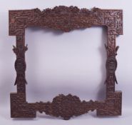 A GOOD LARGE CHINESE CARVED HARDWOOD FRAME, carved with dragons, phoenix, bats and emblems, the