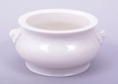 A BLANC DE CHINE PORCELAIN CENSER, with twin lion form handles, 15cm diameter.