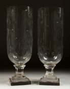 A PAIR OF CUT GLASS STORM LANTERNS on stepped square bases. 13ins high.