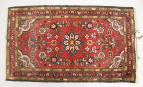 A SMALL PERSIAN RUG, red ground with floral decoration. 4ft 5ins x 2ft 7ins.