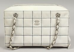 A CREAM PADDED BAG with leather chrome handle. 29cm long.