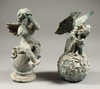 A PAIR OF PAINTED CAST IRON FAIRIES on a ball. 12ins high.