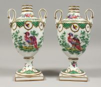 A PAIR OF SAMSON PORCELAIN TWO HANDLED URN SHAPED VASES painted with birds, on square legs. 9.5ins