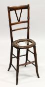 A 19TH CENTURY BEECH FRAMED AND CANE WORK SEATED CORRECTION CHAIR (SEAT A. F.). 3ft 2ins high