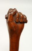 A FOLK ART CLENCHED FIST WALKING STICK 35ins long.