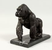 A BRONZE GORILLA on a marble base. 6ins high.