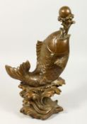 A LARGE CHINESE BRONZE CARP juggling a ball. 16ins high.