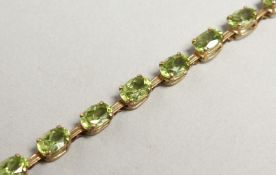 A GOLD AND PERIDOT LINE BRACELET.