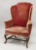 A GEORGE III MAHOGANY FRAMED WING ARMCHAIR, with crimson velvet upholstery, carved cabriole front