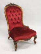 A VICTORIAN WALNUT FRAMED BUTTON BACK ARMCHAIR, on carved cabriole legs with castors.