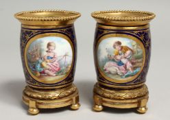 A VERY GOOD PAIR OF SMALL SEVRES VASES with ormolu panels, the porcelain edged in gilt and painted
