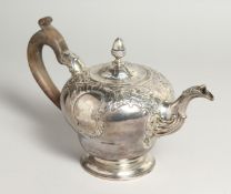 A GEORGE II CIRCULAR TEA POT AND COVER with repousse decoration and pineapple finial. London