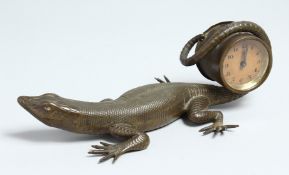 A GOOD BRONZE LIZARD holding a clock in its tail. 9.5ins long.