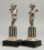 A SUPERB PAIR OF 19TH CENTURY SILVER AND ENAMEL CUPIDS on columns and square bases. 16cm high.
