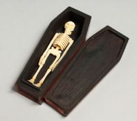 A SMALL WOODEN COFFIN AND BONE SKELETON, 12.5cm long.