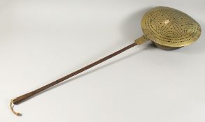 A 17TH - 18TH CENTURY DUTCH BRASS CIRCULAR WARMING PAN with metal handle. 40ins long.