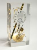 A CLOCK SCULPTURAL PIECE of watch movements, in a Perspex case. 5.25ins high.