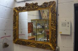 A decorative Chinese carved and pierced gilt framed mirror.