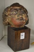 A 17th century carved limewood cherub's head on later stand.