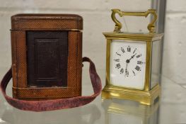 A brass carriage clock with leather carrying case and key.