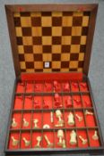A chess board / storage box containing numerous chess pieces.