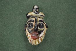 A small, possibly Roman, glass amulet modelled as a mask.