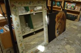 A decoratively framed mirror and a print of a lion.