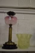 A Victorian brass oil lamp with pink glass reservoir and Vaseline glass shade.