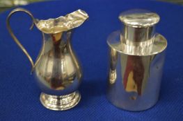 A small silver cream jug and a silver tea canister and cover.