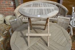 A small circular teak folding garden table.