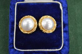 A pair of decorative ear studs with pearl centres, stamped 18ct. Gross weight 12 grams